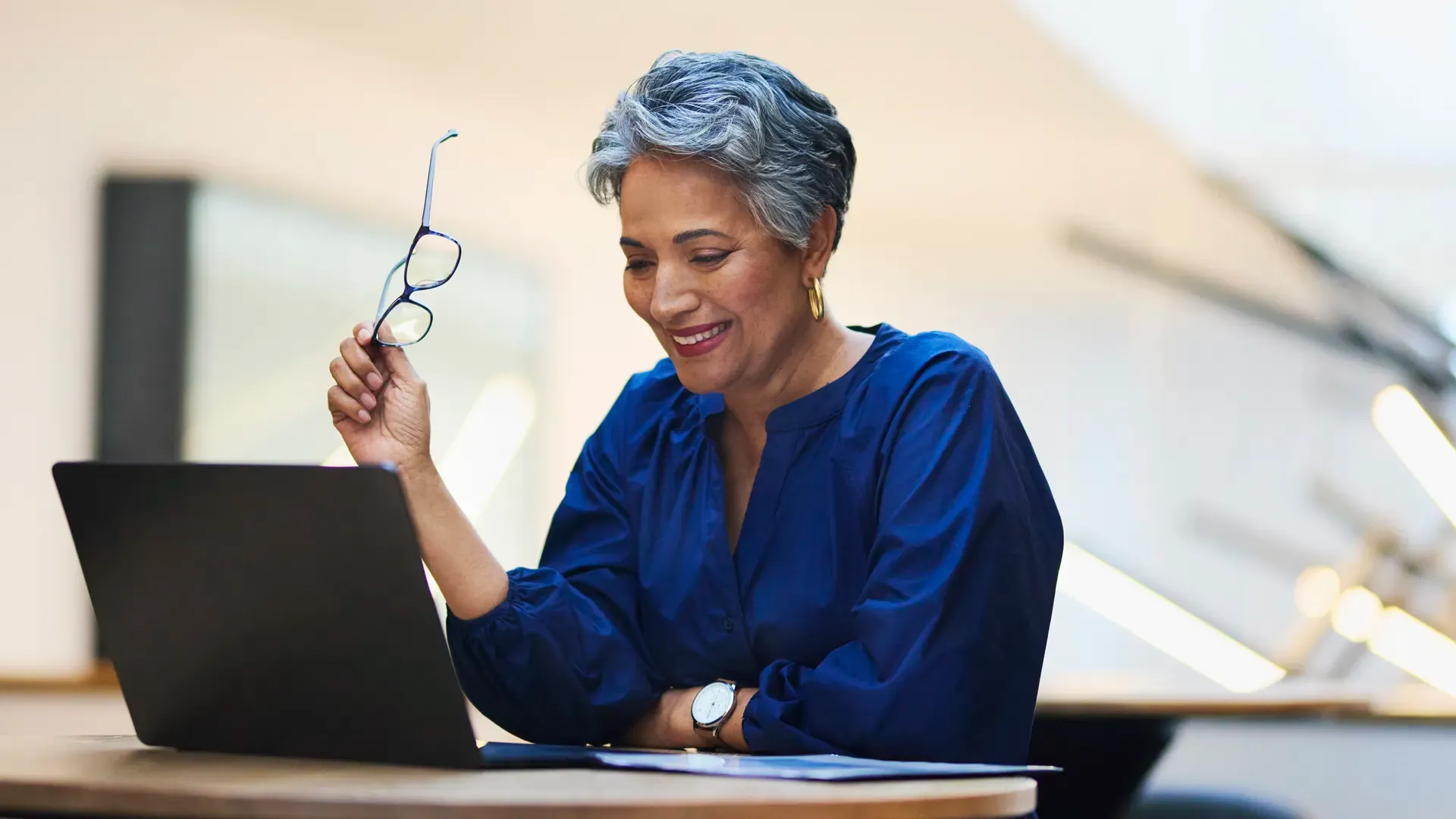 Woman looking at laptop while holding glasses
